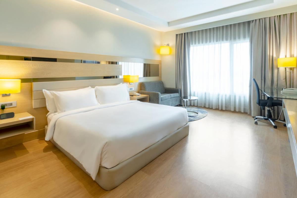 a bedroom with a large white bed and a desk at Holiday Inn Agra MG Road an IHG Hotel in Agra
