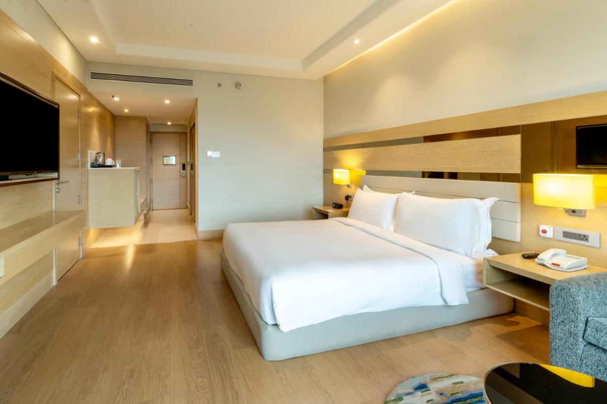 a hotel room with a large white bed and a couch at Holiday Inn Agra MG Road an IHG Hotel in Agra