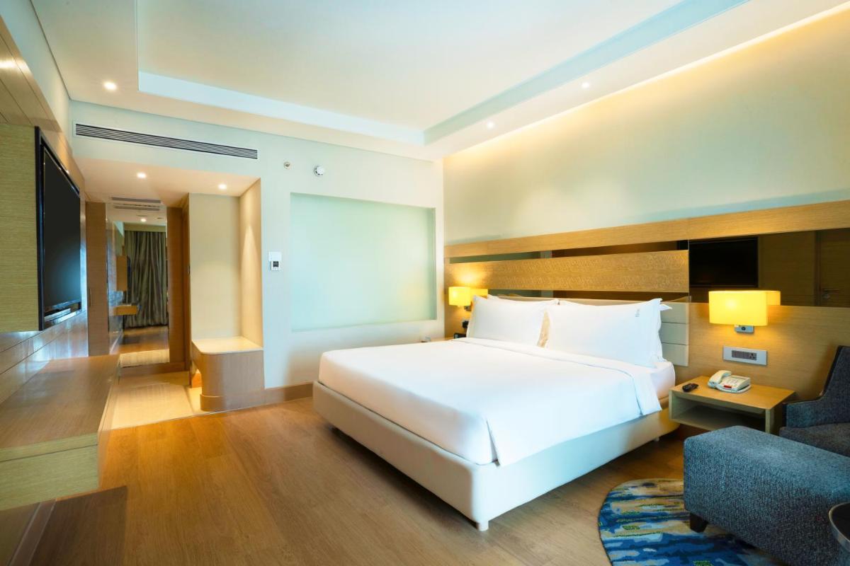 a bedroom with a large white bed and a couch at Holiday Inn Agra MG Road an IHG Hotel in Agra