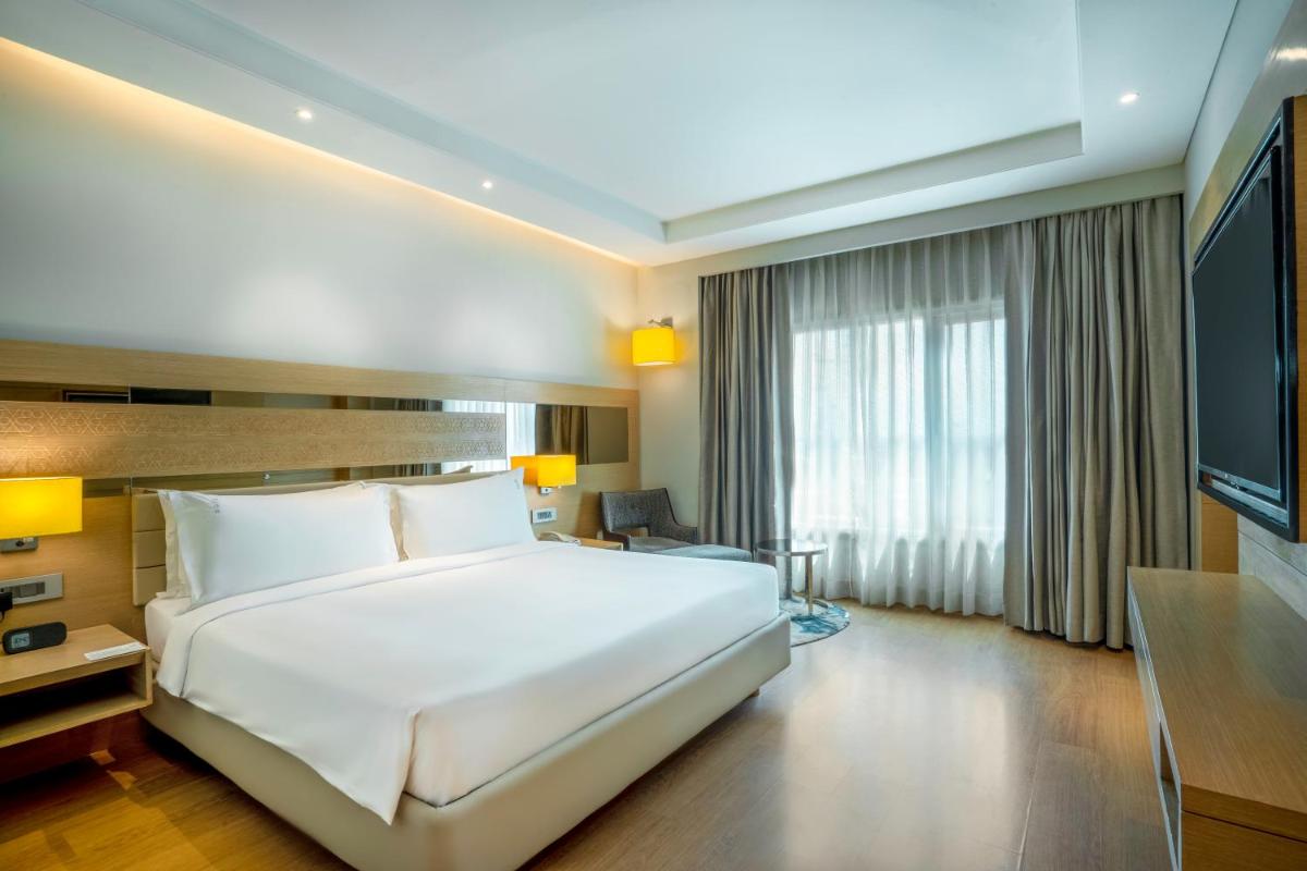 a hotel room with a large bed and a television at Holiday Inn Agra MG Road an IHG Hotel in Agra