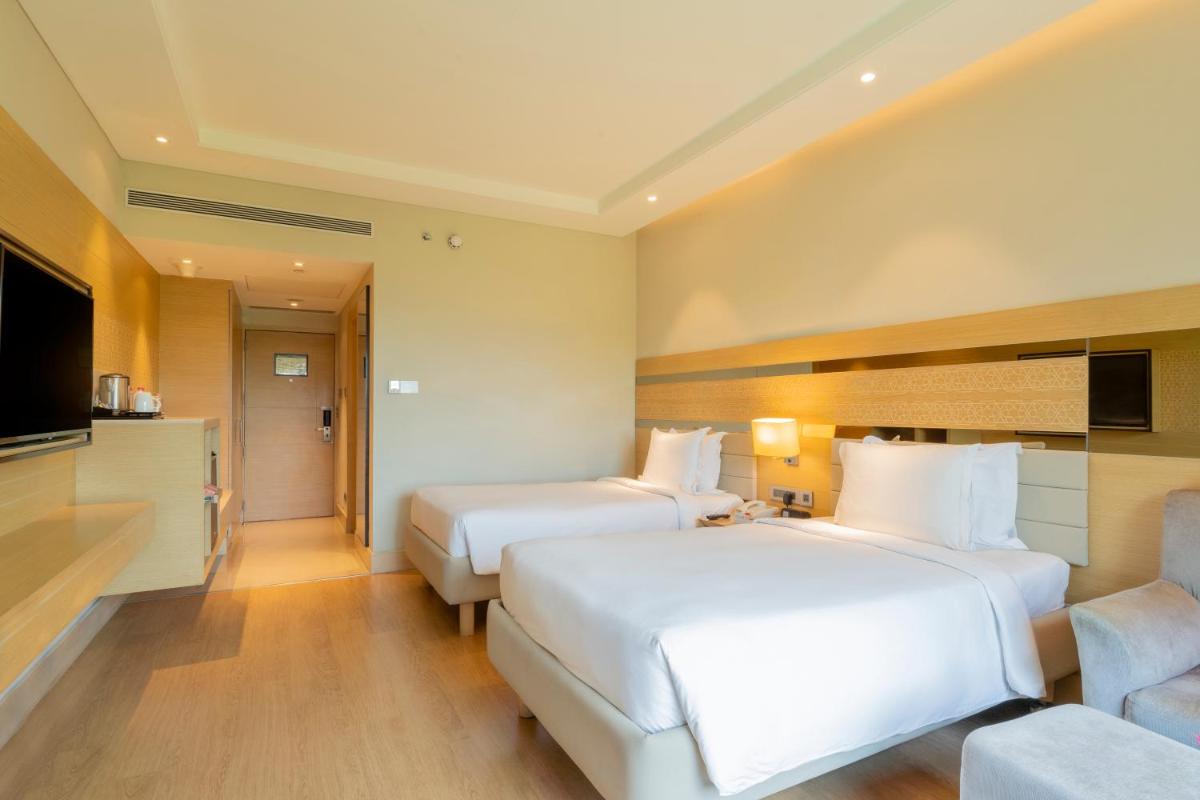 a hotel room with two beds and a flat screen tv at Holiday Inn Agra MG Road an IHG Hotel in Agra