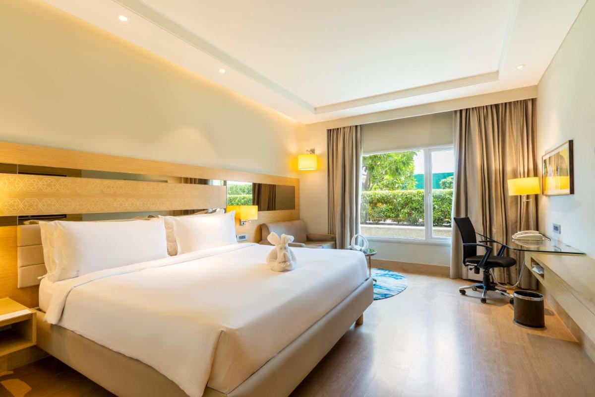 a hotel room with a large bed and a desk at Holiday Inn Agra MG Road an IHG Hotel in Agra