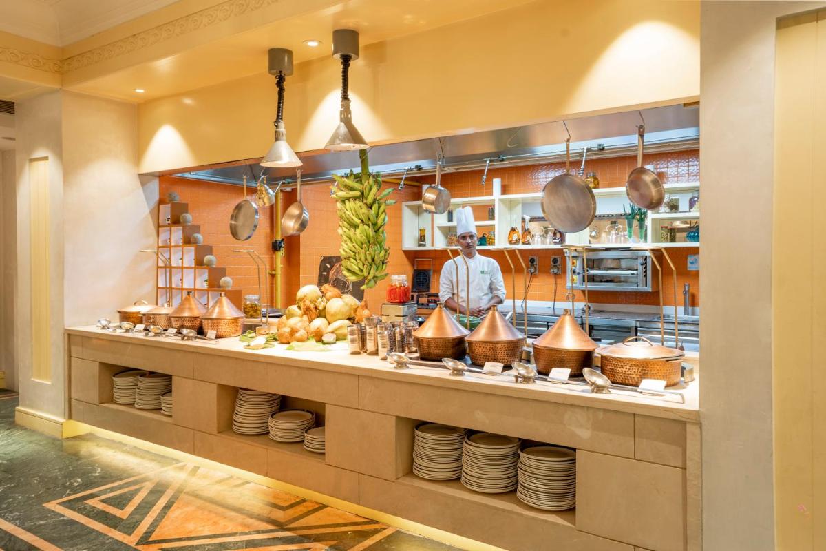 a chef in a kitchen with a counter with plates at Holiday Inn Agra MG Road an IHG Hotel in Agra