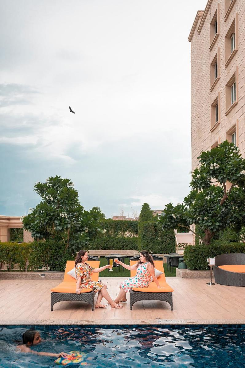 two women sitting on chairs next to a swimming pool at Holiday Inn Agra MG Road an IHG Hotel in Agra