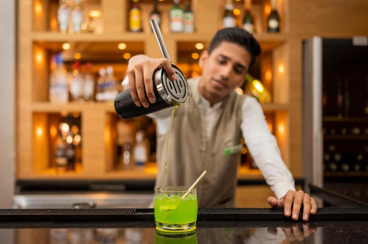 a man is making a drink at a bar at Holiday Inn Agra MG Road an IHG Hotel in Agra