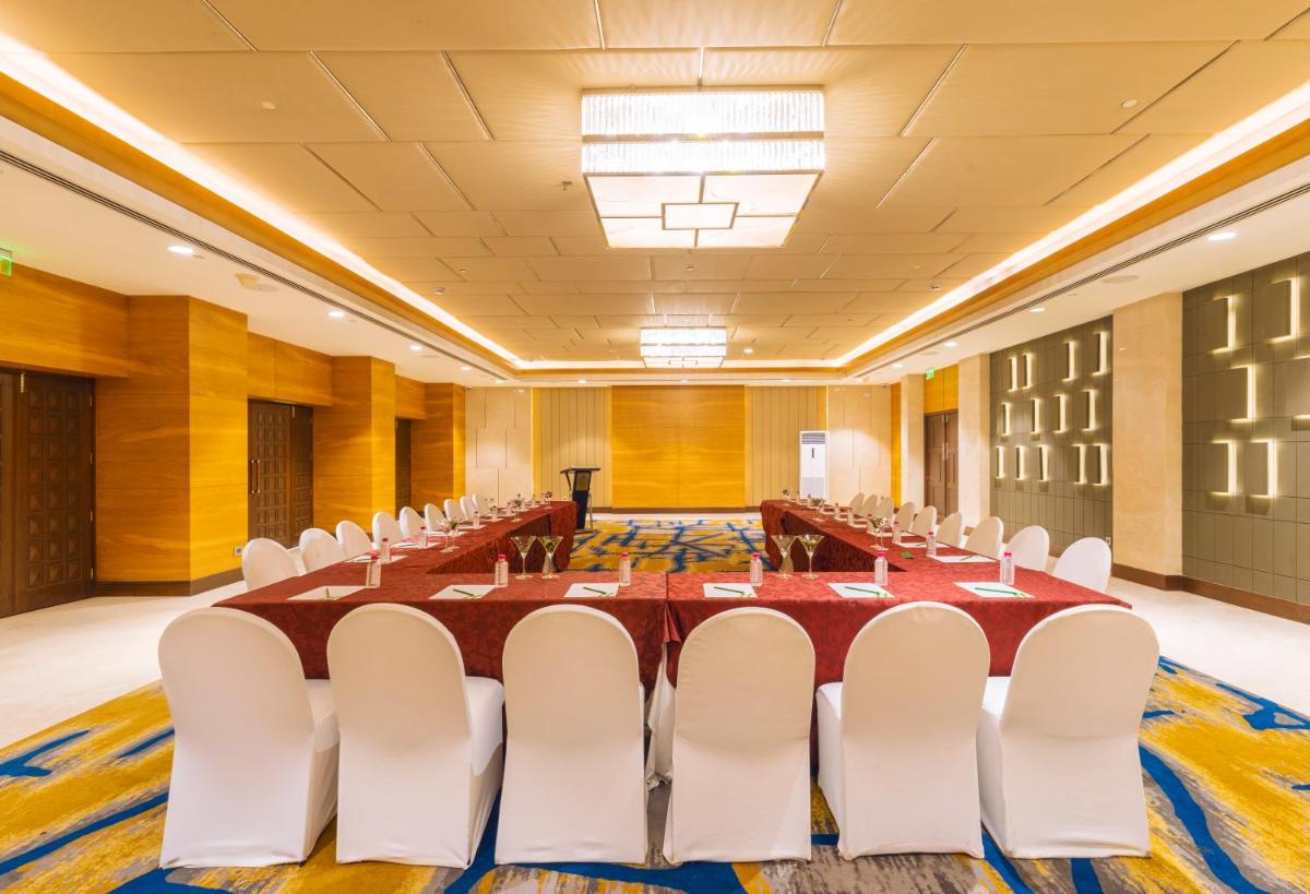 a large conference room with a long table and white chairs at Holiday Inn Agra MG Road an IHG Hotel in Agra