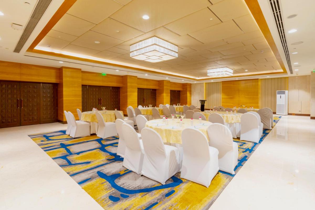 a banquet hall with white tables and white chairs at Holiday Inn Agra MG Road an IHG Hotel in Agra