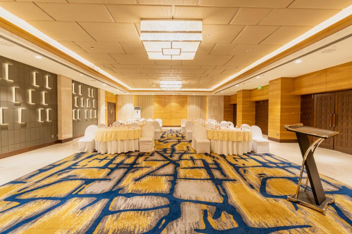 a large banquet hall with white chairs and a large rug at Holiday Inn Agra MG Road an IHG Hotel in Agra