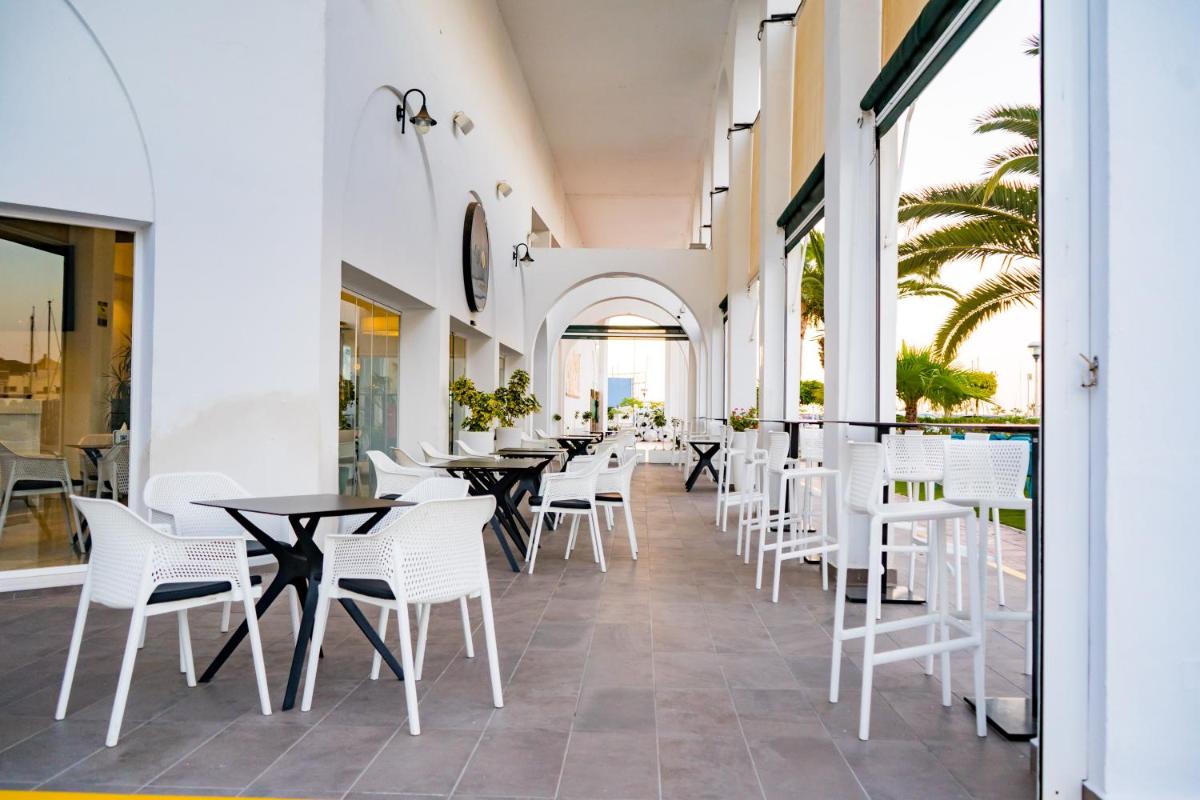 Un restaurante con sillas y mesas blancas y ventanas. en Moon Hotel & SPA., en Aguadulce