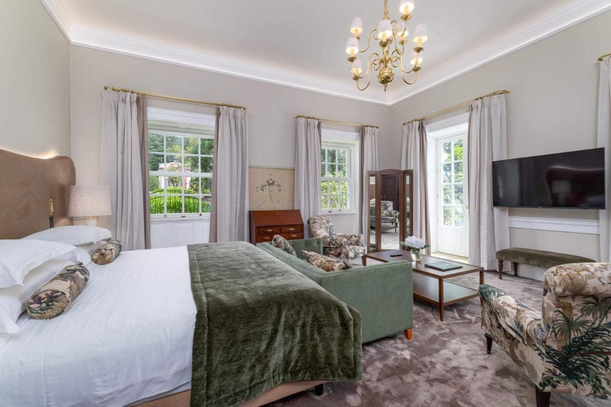um quarto com uma cama grande e uma sala de estar em Casa Velha do Palheiro Relais & Chateaux no Funchal mais 42 fotografias
