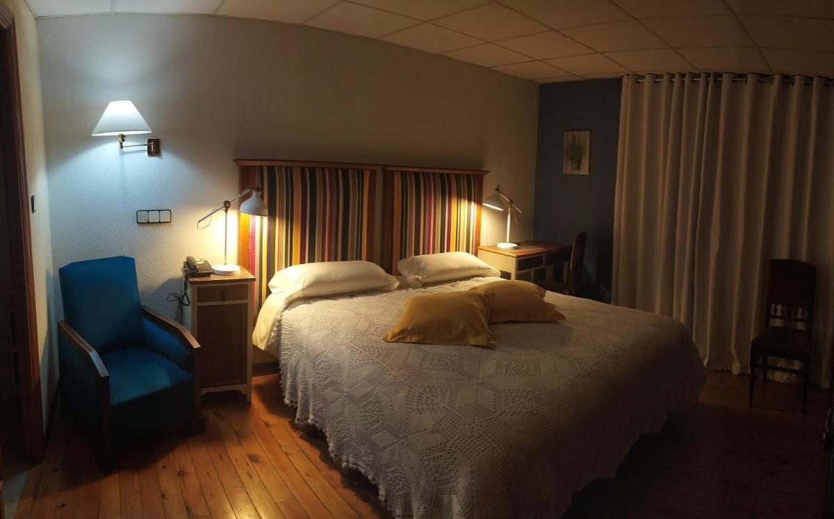 Un dormitorio con una cama y una silla azul. en Balneario de Corconte, en Cabañas de Virtus