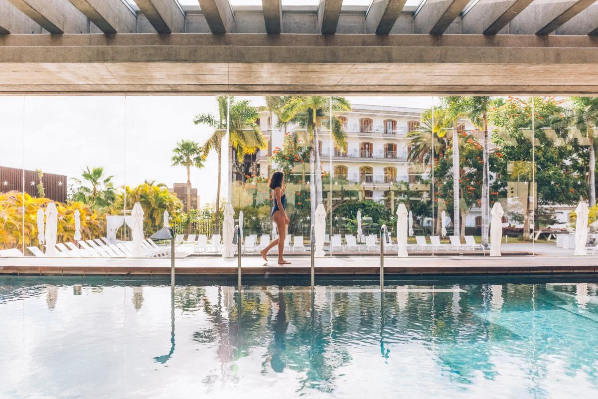 una mujer caminando frente a una piscina en Iberostar Heritage Grand Mencey, en Santa Cruz de Tenerife