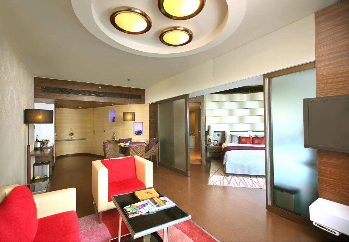 a living room with a red chair and a bedroom at Fortune Select SG Highway, Ahmedabad - Member ITC Hotels' Group in Ahmedabad