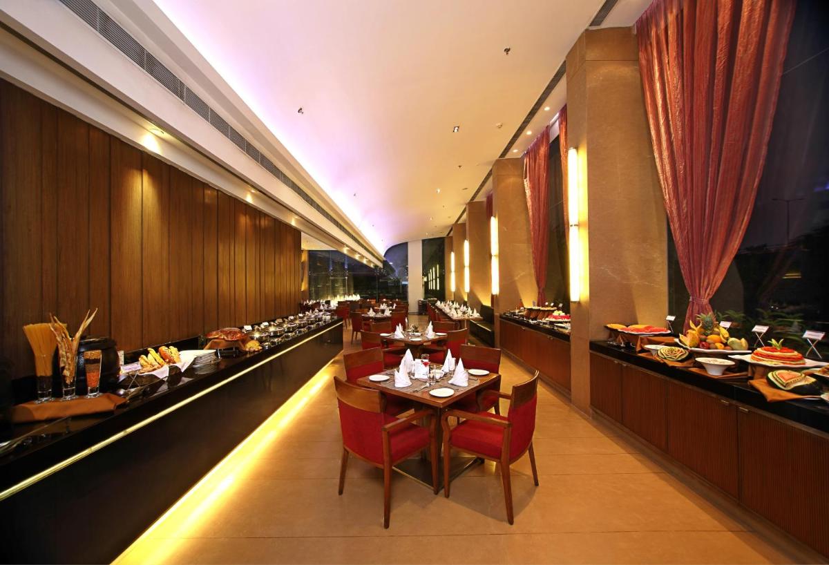 a restaurant with tables and chairs and food on display at Fortune Select SG Highway, Ahmedabad - Member ITC Hotels' Group in Ahmedabad