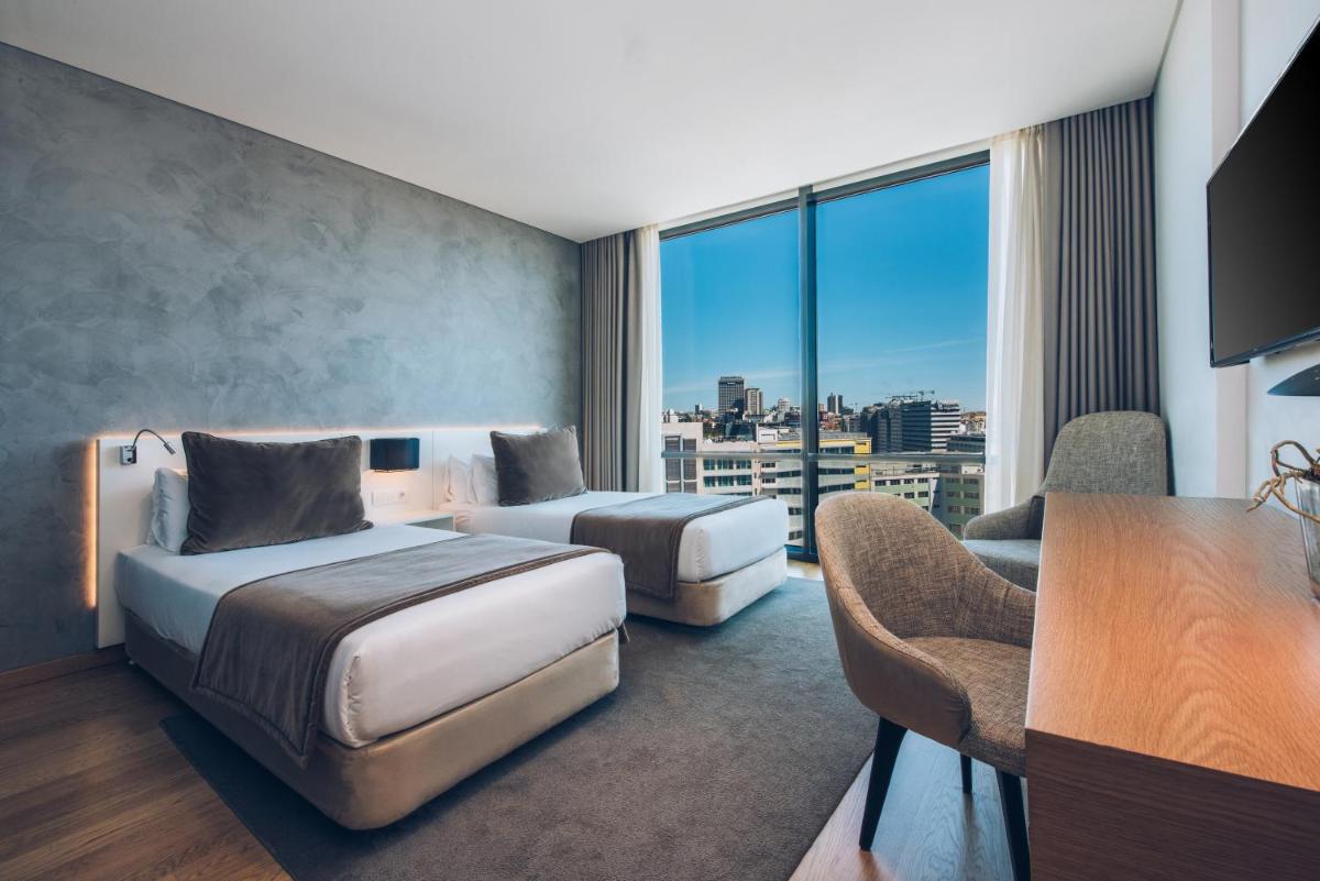 um quarto de hotel com duas camas, uma escrivaninha e uma mesa em Iberostar Selection Lisboa em Lisboa