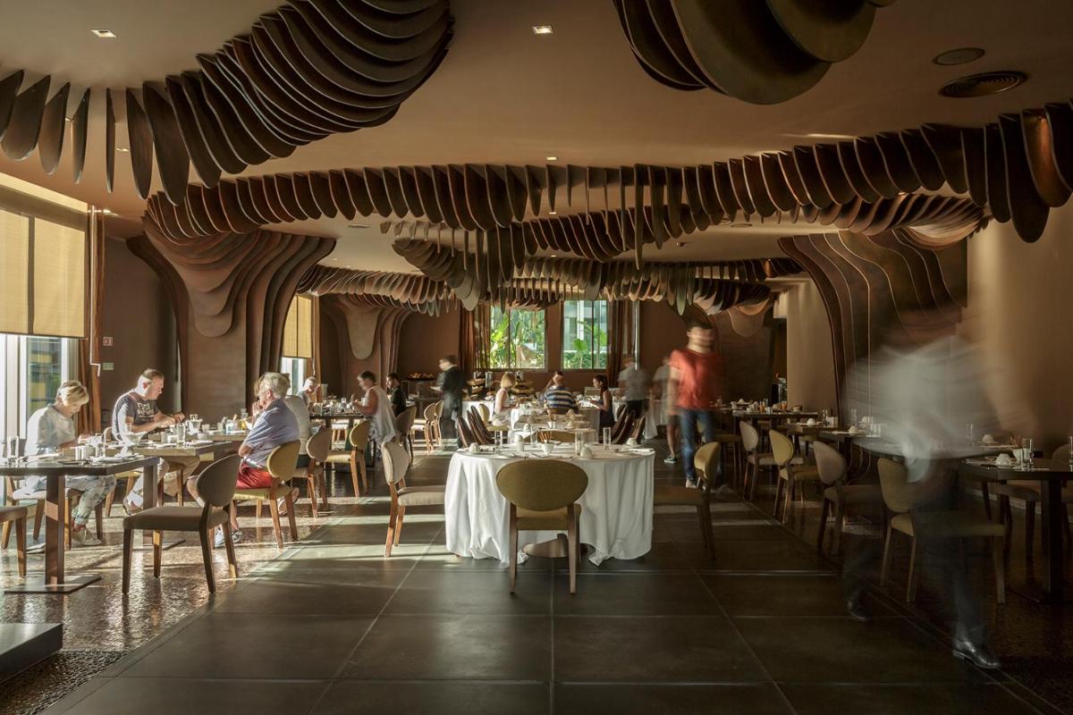 um restaurante com pessoas sentadas em mesas numa sala em The Vine Hotel no Funchal