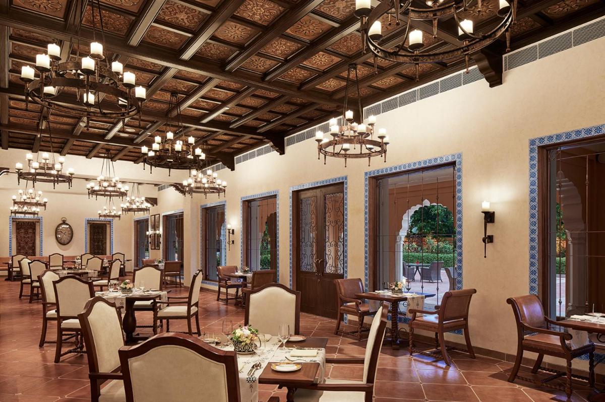 a dining room with tables and chairs and chandeliers at Sawai Man Mahal in Jaipur