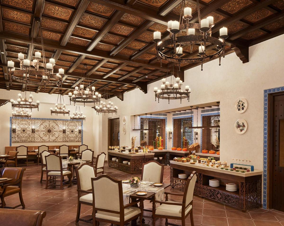 a dining room with tables and chairs and chandeliers at Sawai Man Mahal in Jaipur