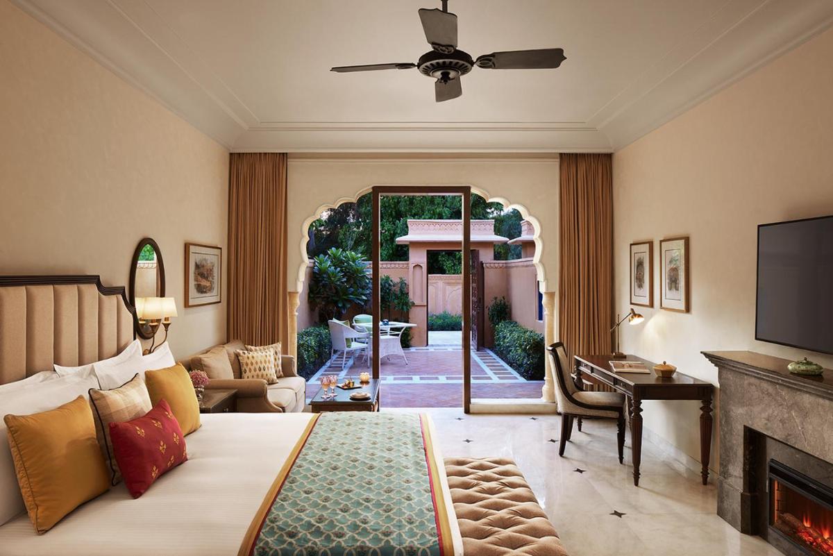 a bedroom with a bed and a living room with a fireplace at Sawai Man Mahal in Jaipur