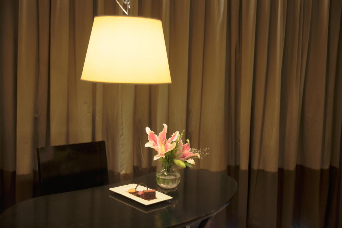 a table with a lamp and a vase with flowers on it at Novotel Kolkata Hotel and Residences in Kolkata a table with a lamp and a vase with flowers on it at Novotel Kolkata Hotel and Residences in Kolkata