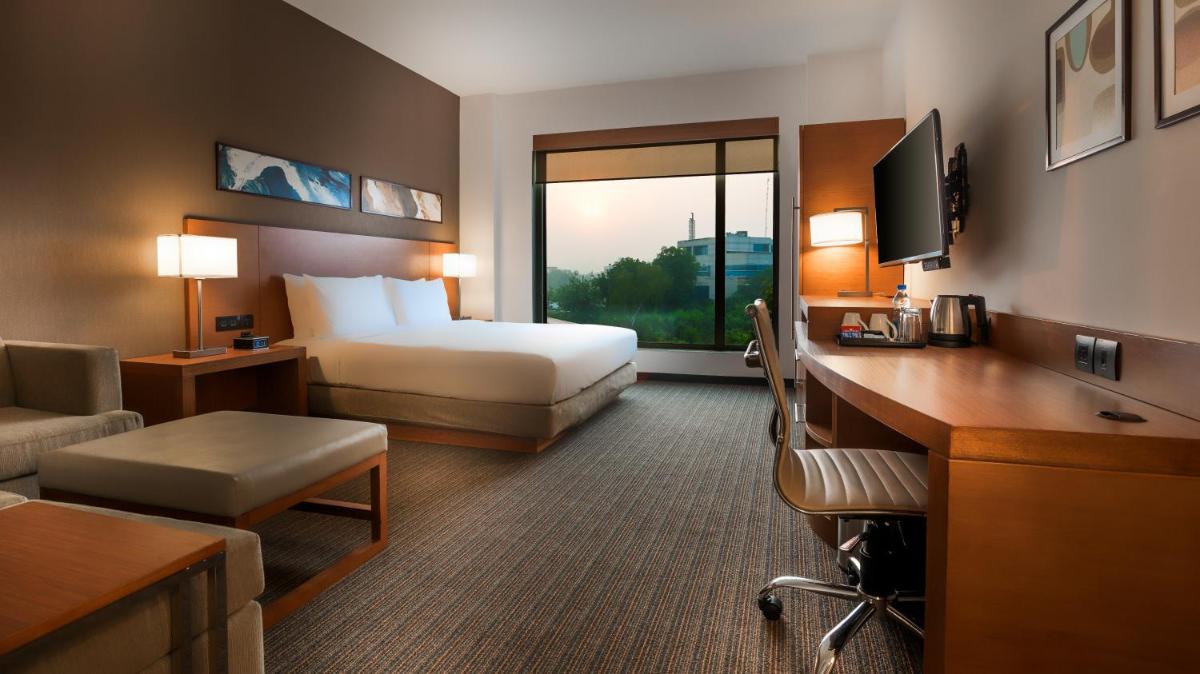 a hotel room with a bedroom with a bed and a desk at Hyatt Place Gurgaon Udyog Vihar in Gurgaon