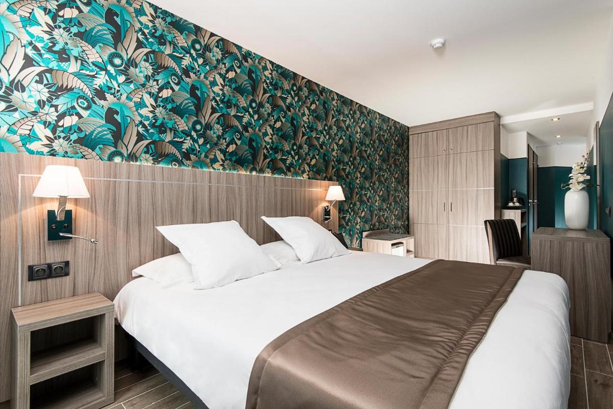 une chambre d'hôtel avec un grand lit et une peinture murale dans l'établissement Unique Hôtel Résidence & Spa, à Saint-Raphaël