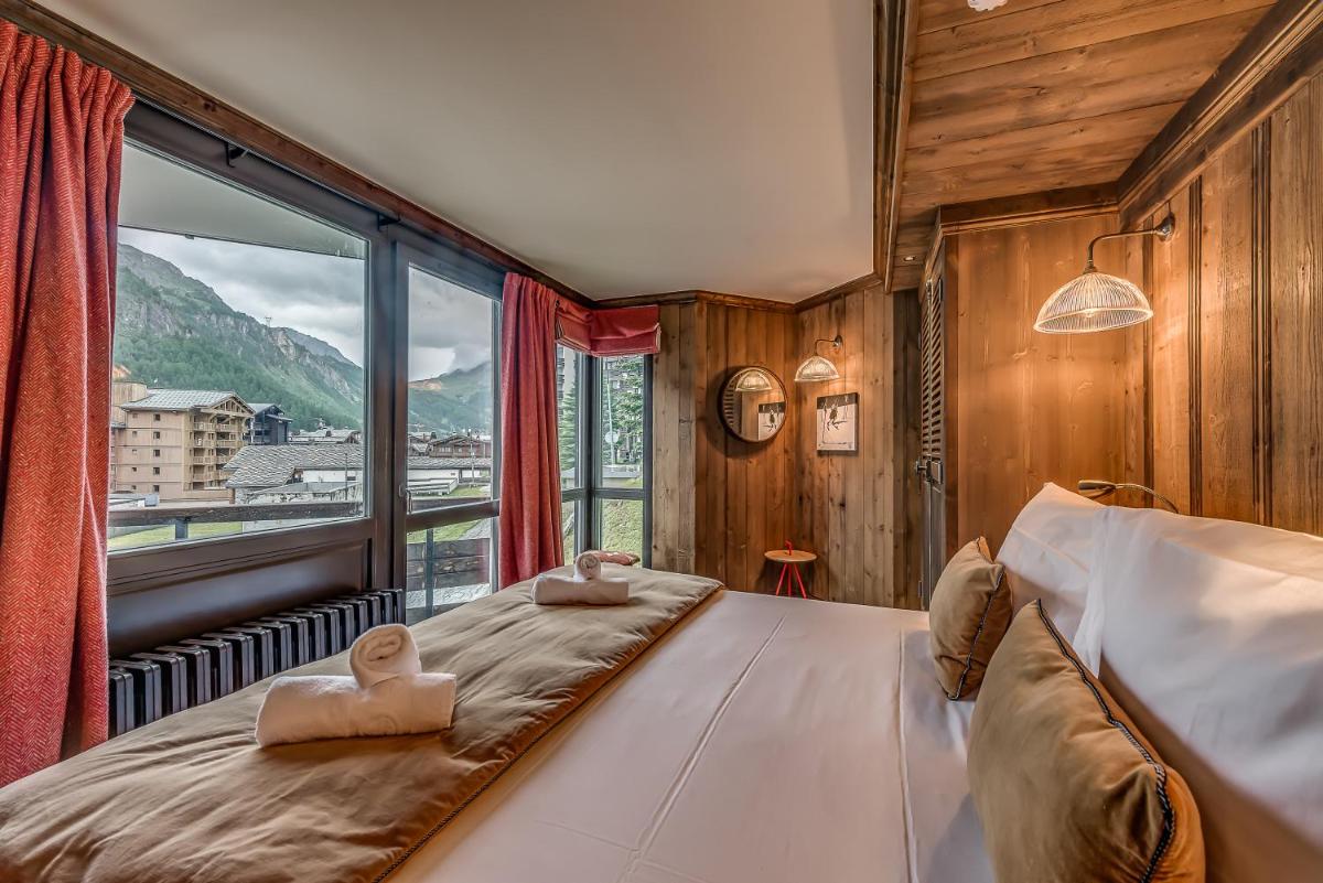 une chambre avec un lit et une grande fenêtre dans l'établissement Hotel & Spa Le Val d'Isère, à Val dʼIsère