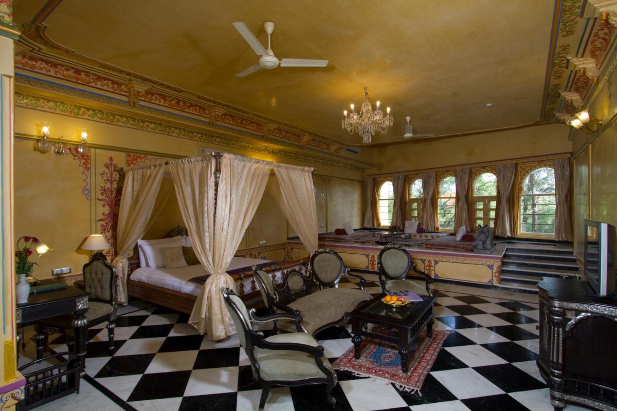 a bedroom with a bed and a checkerboard floor at Chunda Palace in Udaipur