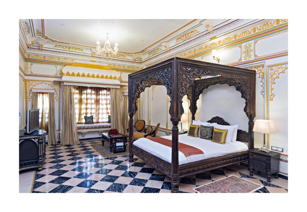 a bedroom with a canopy bed in a room at Chunda Palace in Udaipur