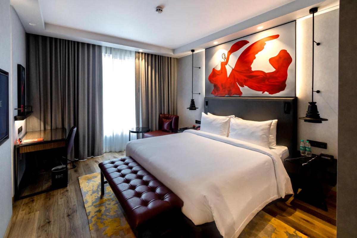 a hotel room with a large bed and a couch at Radisson RED Chandigarh Mohali in Chandīgarh