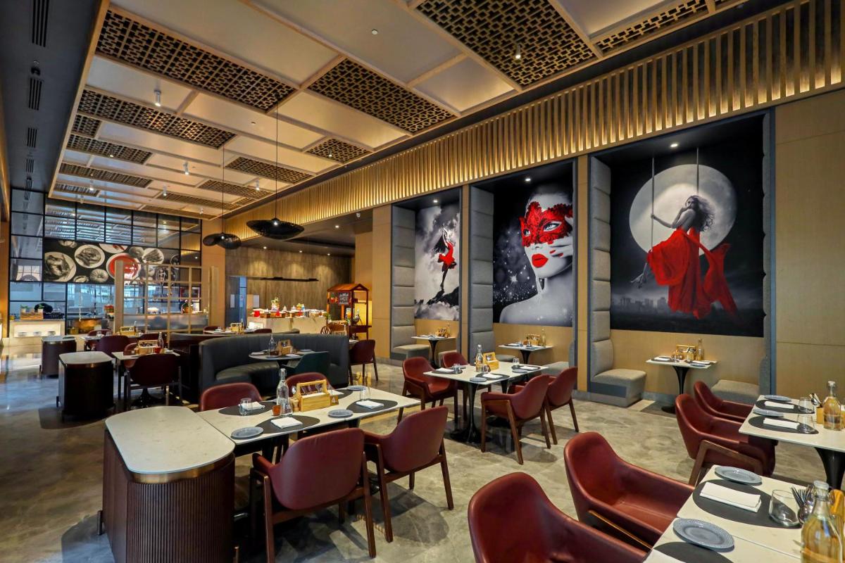 a restaurant with tables and chairs and paintings on the walls at Radisson RED Chandigarh Mohali in Chandīgarh