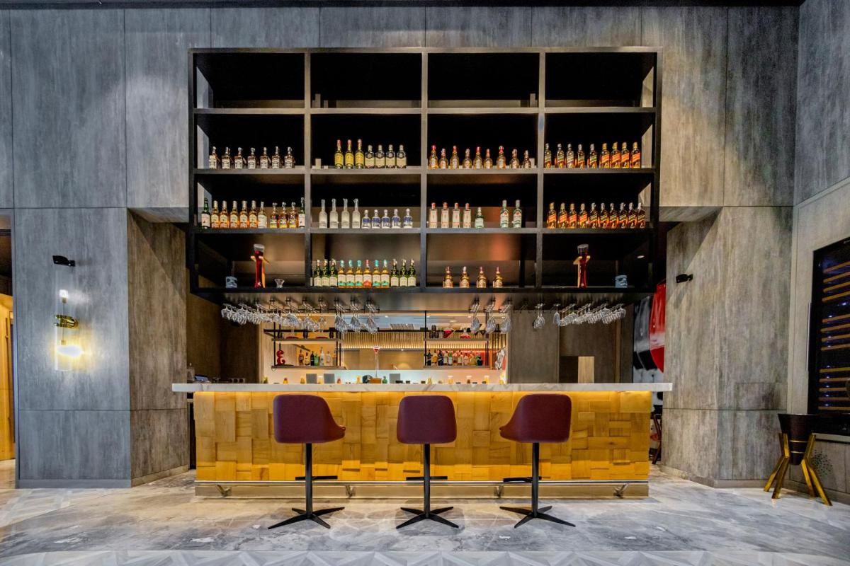 a bar with three stools in front of a counter at Radisson RED Chandigarh Mohali in Chandīgarh