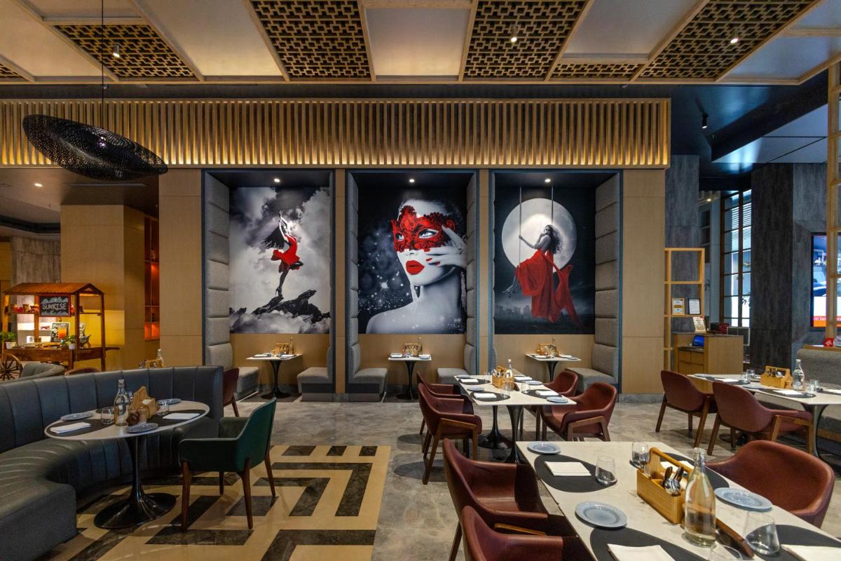 a restaurant with tables and chairs and paintings on the walls at Radisson RED Chandigarh Mohali in Chandīgarh