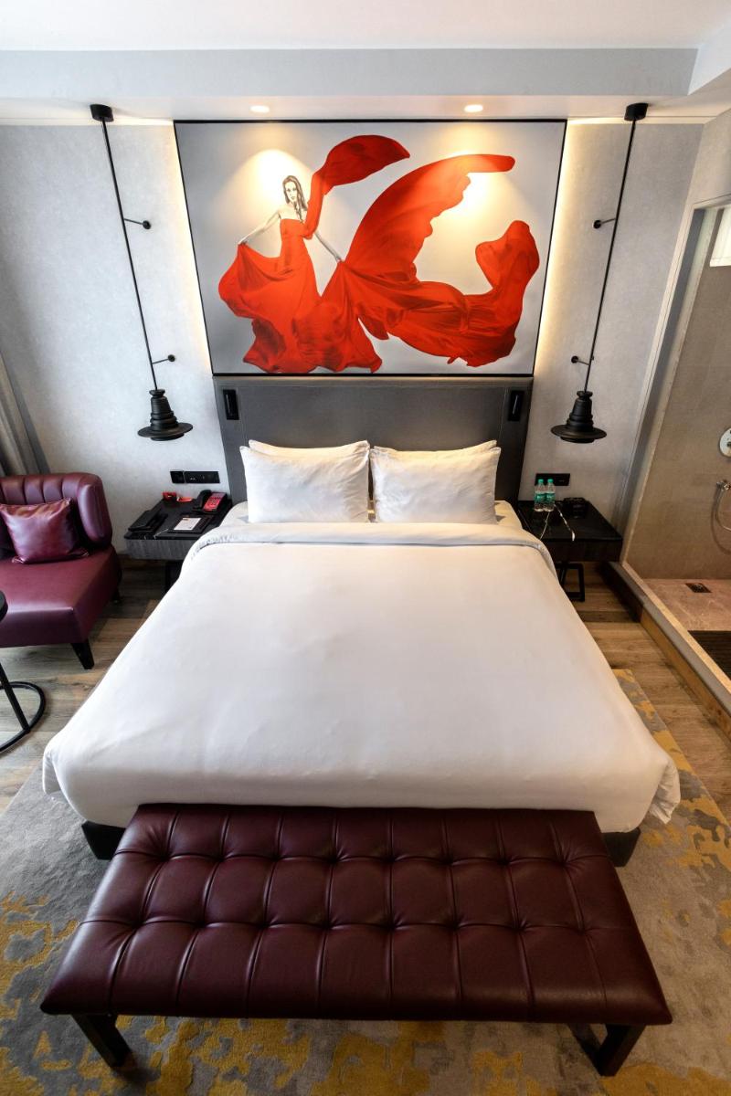 a bedroom with a large bed with a brown leather seat at Radisson RED Chandigarh Mohali in Chandīgarh