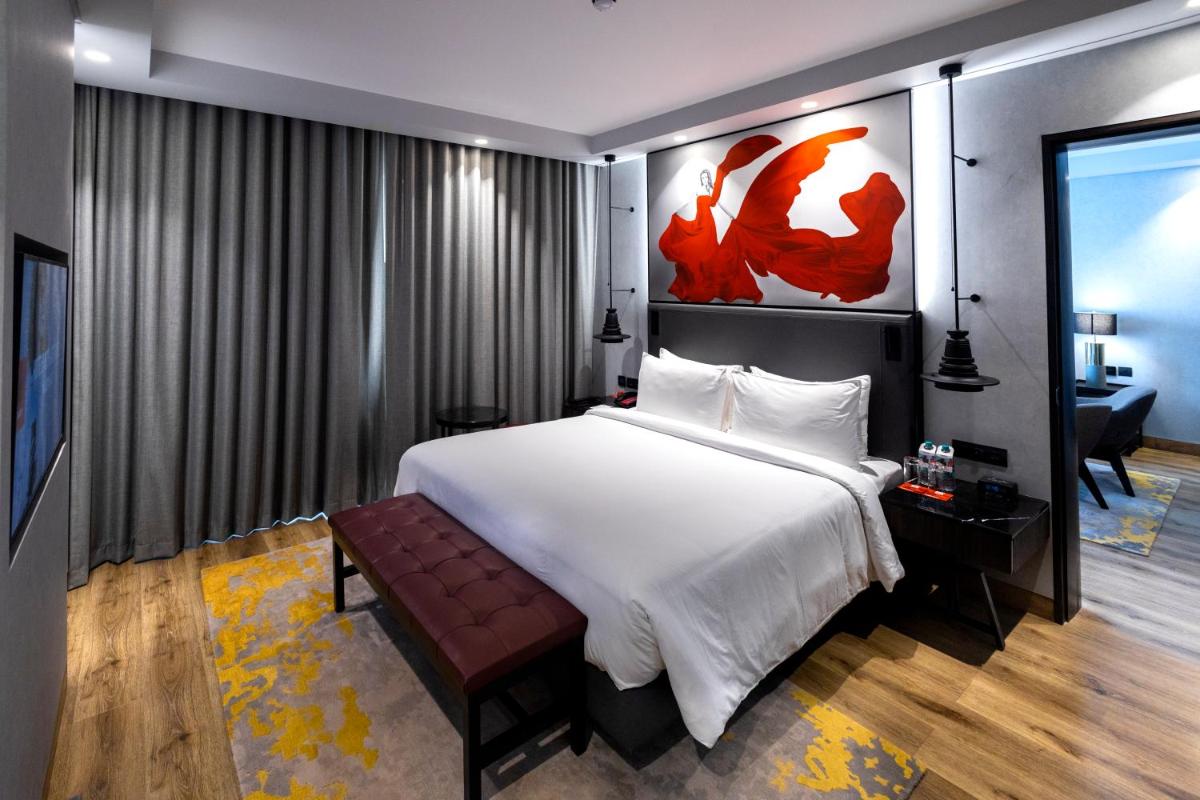a bedroom with a large white bed and a bench at Radisson RED Chandigarh Mohali in Chandīgarh