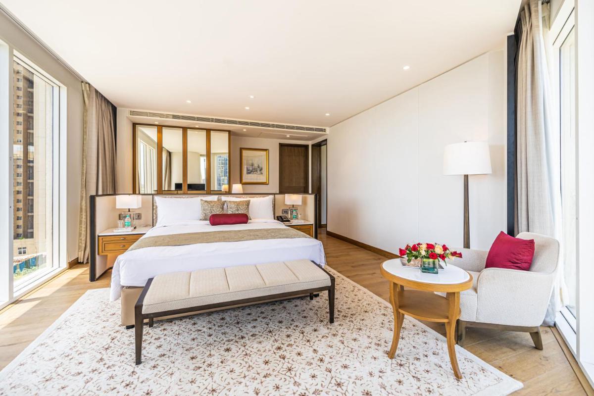 a bedroom with a bed and a couch and a table at The Leela Bhartiya City Bengaluru in Bengaluru a bedroom with a bed and a couch and a table at The Leela Bhartiya City Bengaluru in Bengaluru