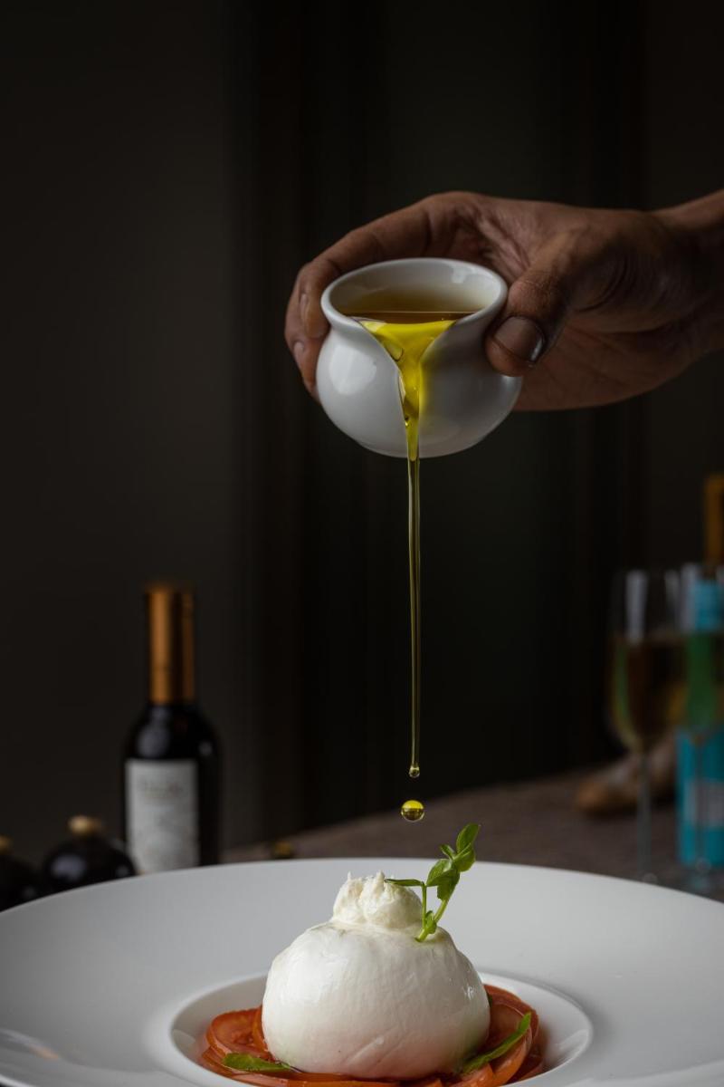 a person is holding a cup of honey over a dessert at The Leela Bhartiya City Bengaluru in Bengaluru a person is holding a cup of honey over a dessert at The Leela Bhartiya City Bengaluru in Bengaluru