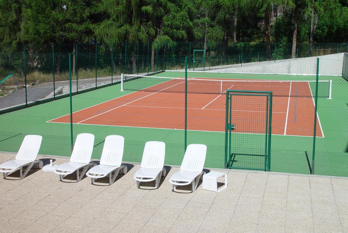 - une rangée de chaises blanches sur un court de tennis dans l'établissement Hotel et Résidence Le Clos Cerdan, à Mont-Louis