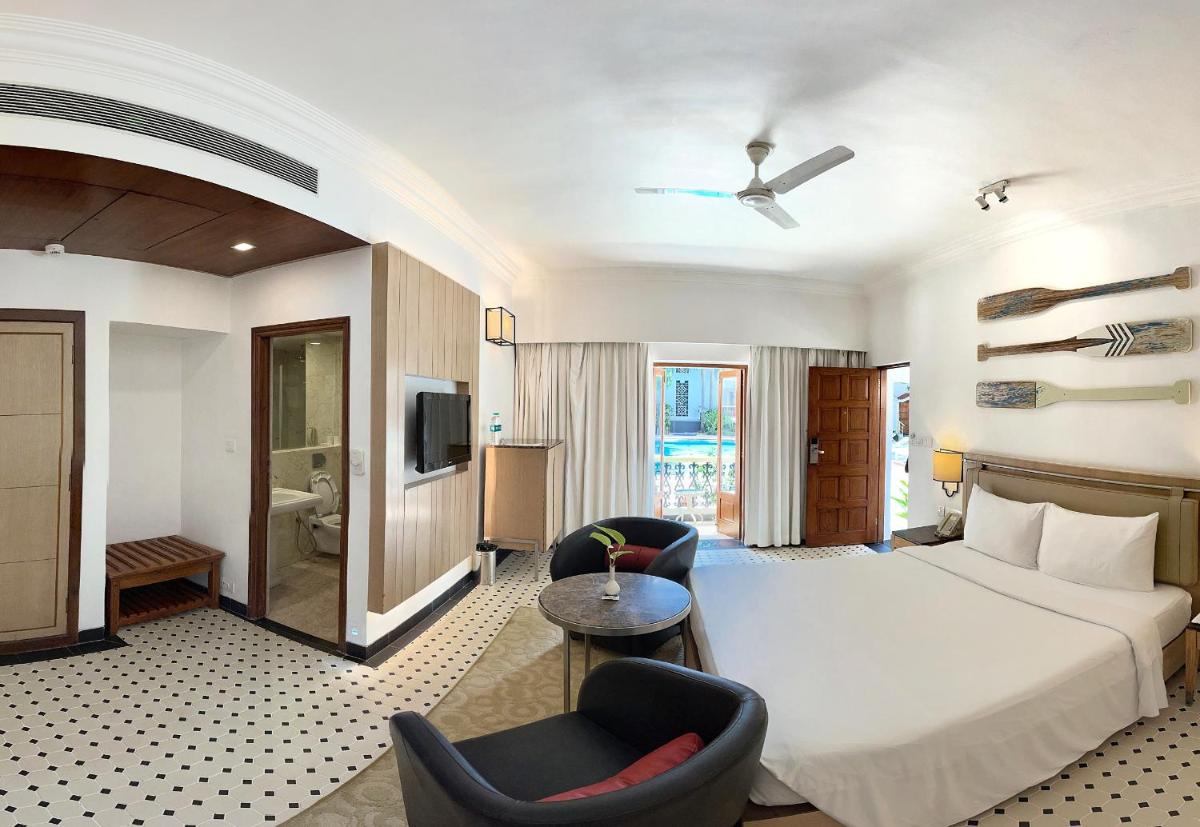 a hotel room with a bed and two chairs at Radisson Goa Candolim in Candolim
