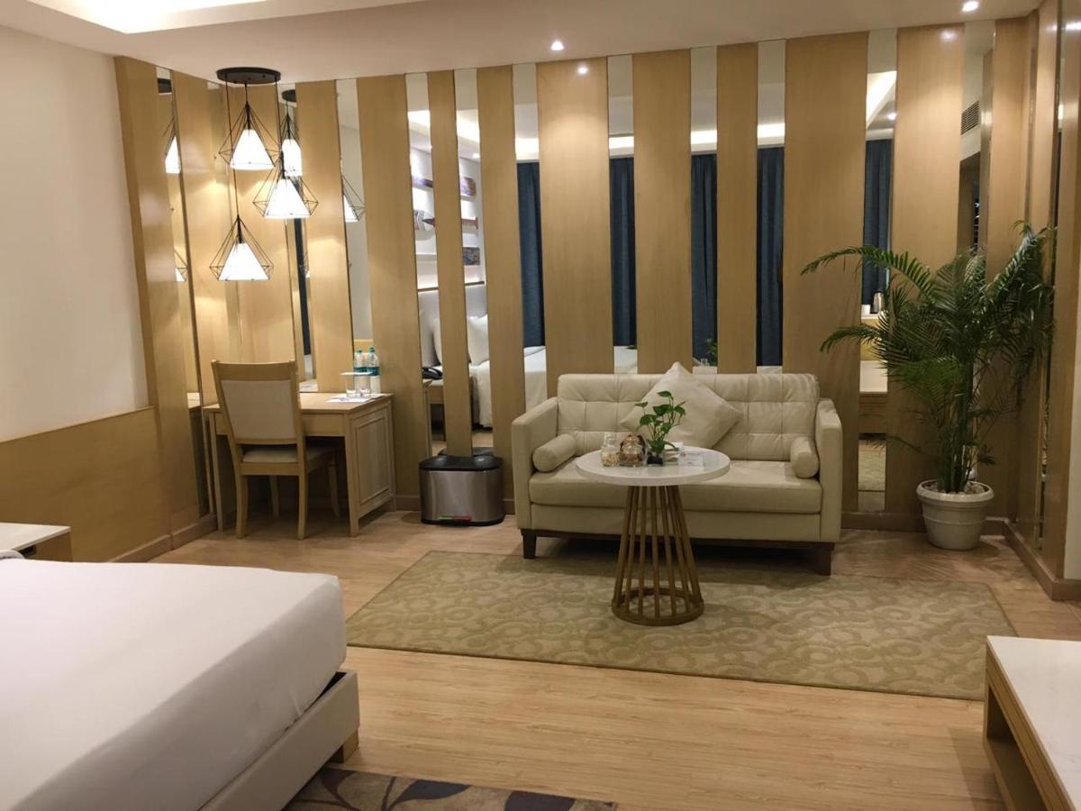 a hotel room with a bed and a couch and a table at Radisson Goa Candolim in Candolim