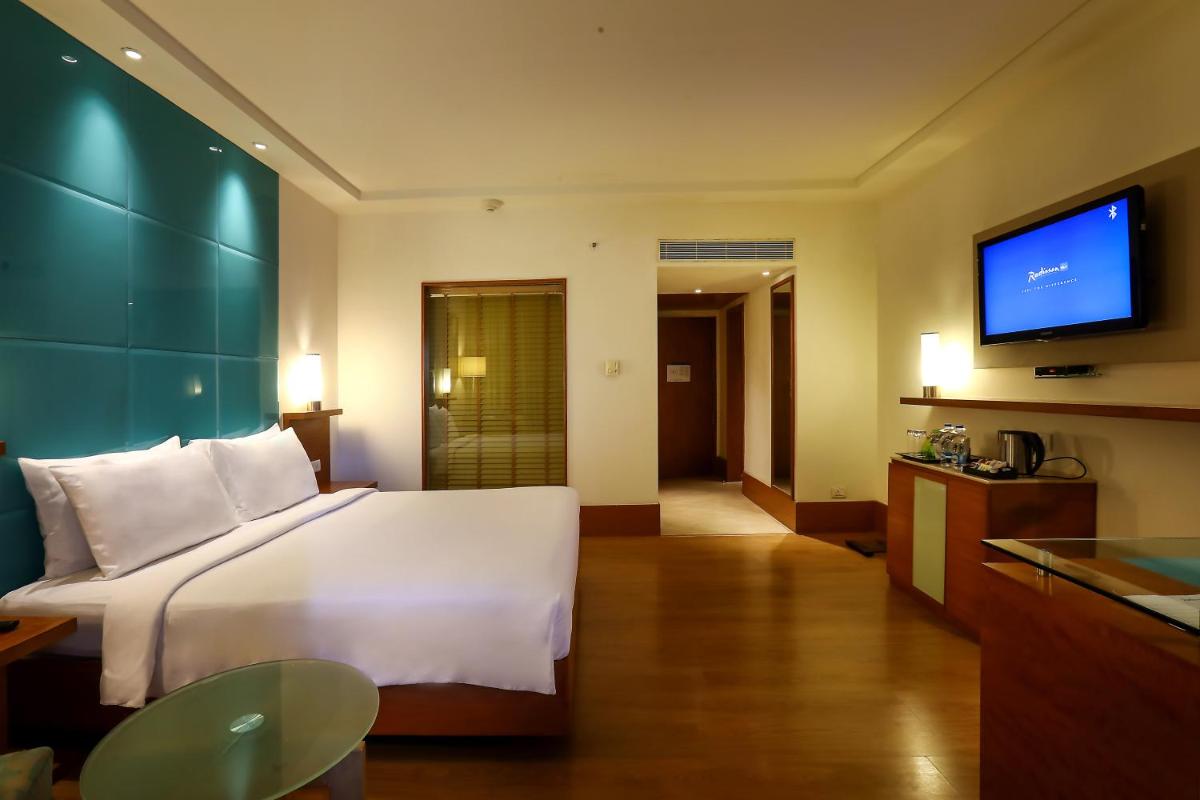 a hotel room with a bed and a flat screen tv at Radisson Blu Hotel Chennai City Centre in Chennai a hotel room with a bed and a flat screen tv at Radisson Blu Hotel Chennai City Centre in Chennai