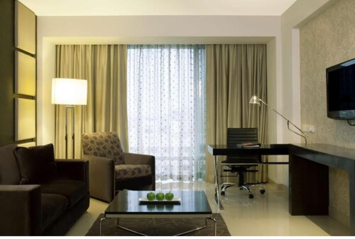 a living room with a couch and a desk in a hotel room at Radisson Blu Hotel Pune Kharadi in Pune
