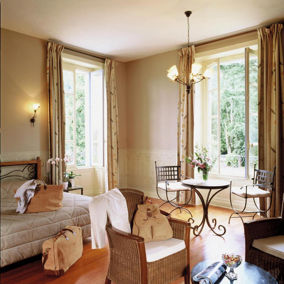 une chambre avec un lit, une table et des chaises dans l'établissement Logis Le Parc Hotel & Spa, à Château-Gontier