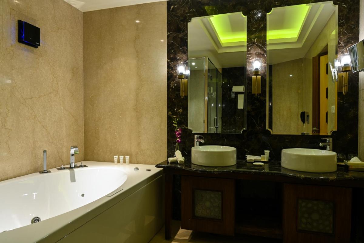 a bathroom with two sinks and a tub and a large mirror at Radisson Jodhpur in Jodhpur