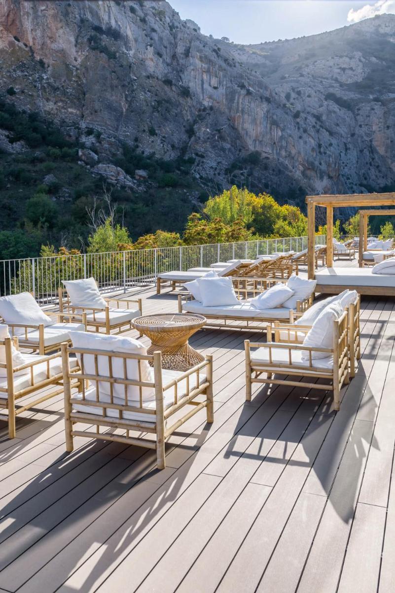 un grupo de sillas y mesas en una terraza de madera en Balneario Segura de Baños, en Segura de los Baños