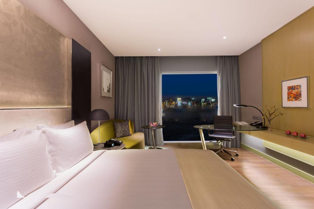 a hotel room with a bed and a desk and a window at Holiday Inn New Delhi Aerocity by IHG in New Delhi