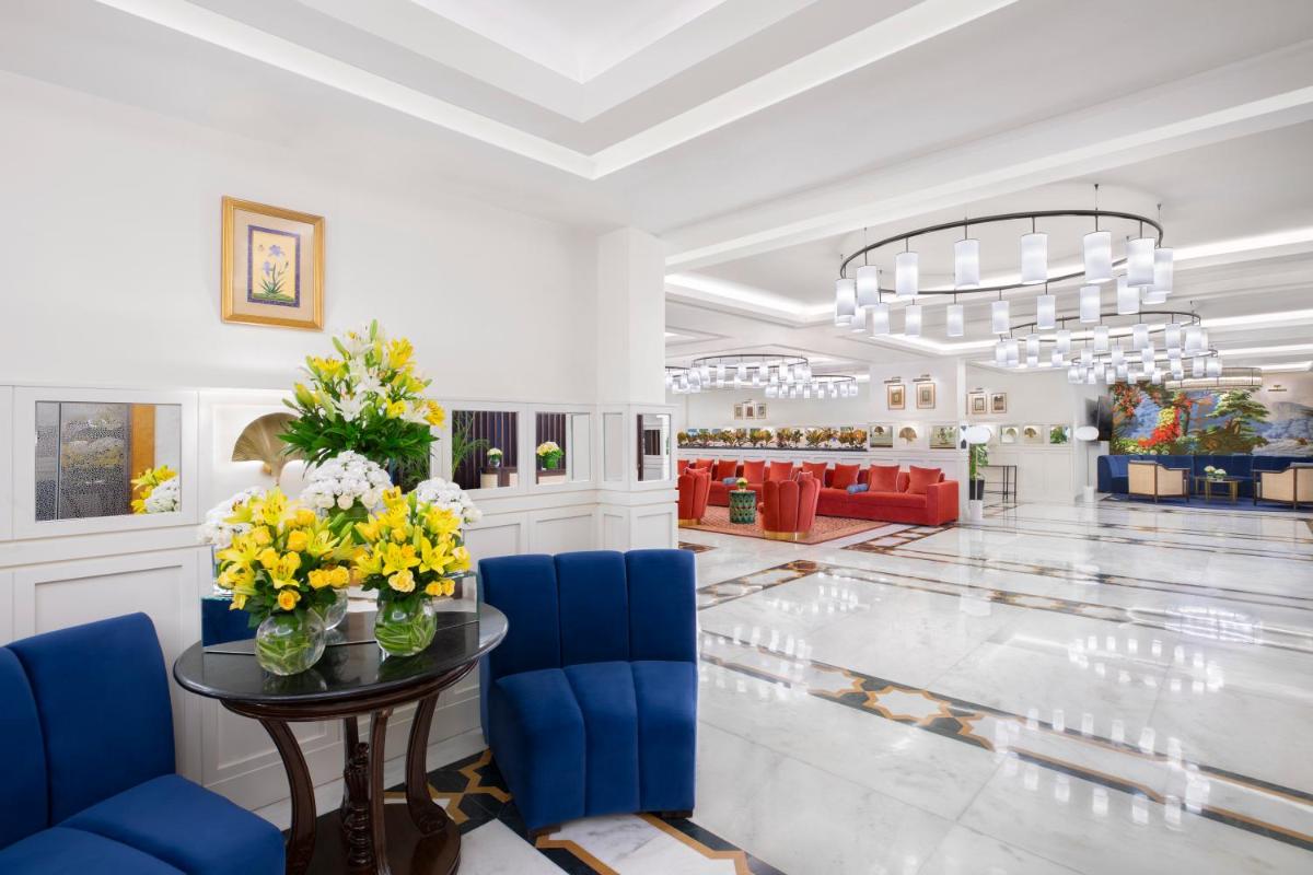 a lobby with a table with flowers and blue chairs at Tajview, Agra-IHCL SeleQtions in Agra
