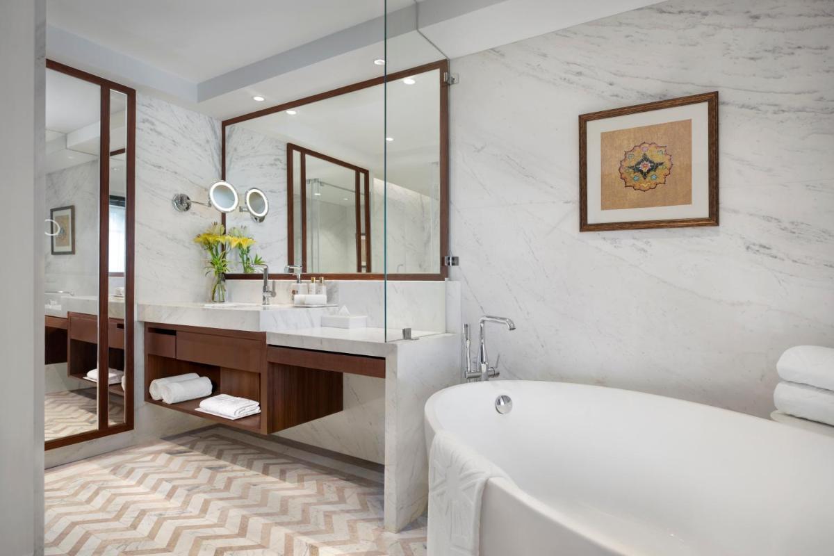 a bathroom with a tub and a large mirror at Tajview, Agra-IHCL SeleQtions in Agra