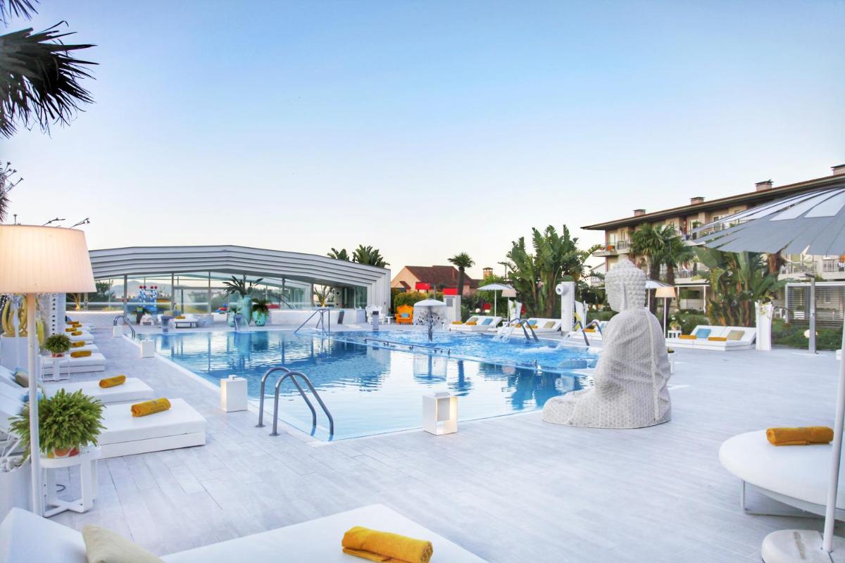 una piscina en un complejo con muebles blancos y un edificio en Augusta Eco Wellness Resort 4 Superior, en Sanxenxo