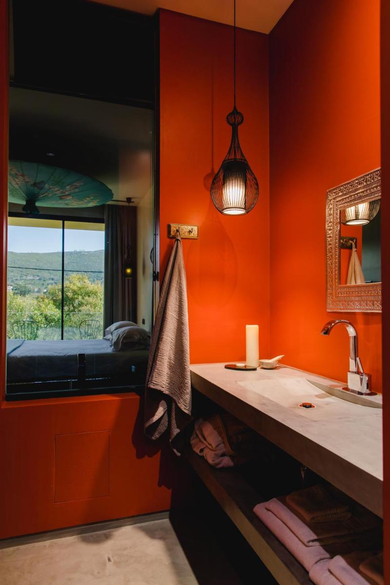 uma casa de banho com paredes cor-de-laranja, um lavatório e um espelho. em Cooking and Nature - Emotional Hotel em Alvados